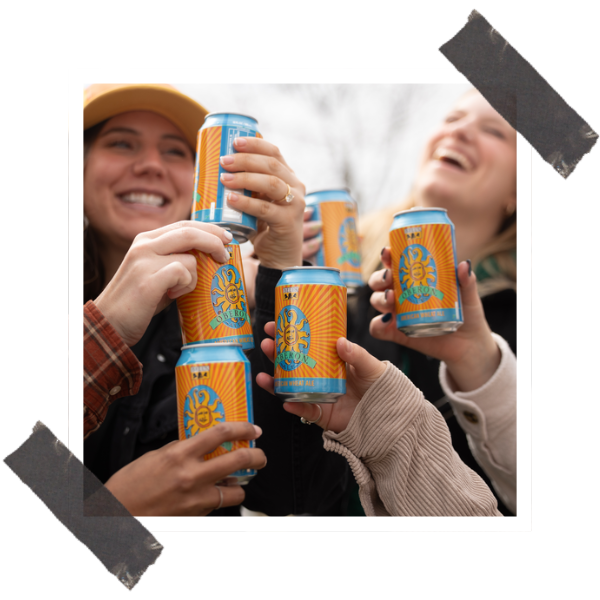 Bell’s Brewery Releasing Oberon 2025 & New Oberon Light 30 A group of friends, two of which are female and pictured doing a cheers with Bell's Brewery Oberon cans.