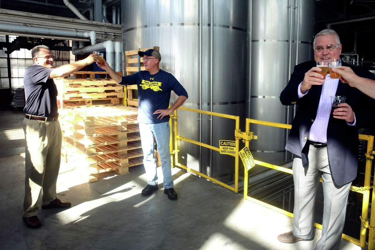 Two Roads Synopsis Red Berries Coming From Area Two / Conn Artists 2021 / Two Conn Ale / Chocolate Cookie Stout / Roadsmary’s Step Child / Roadsmary’s Baby 15 Master Brewer Phil Markowski, center, raises a toast as he leads a tour of the Two Roads Brewing Company brewery, in Stratford, Conn. Oct. 12, 2021. Markowski and Two Roads staff were joined by representatives from the University of Connecticut for the introduction of their new TwoConn Ale.