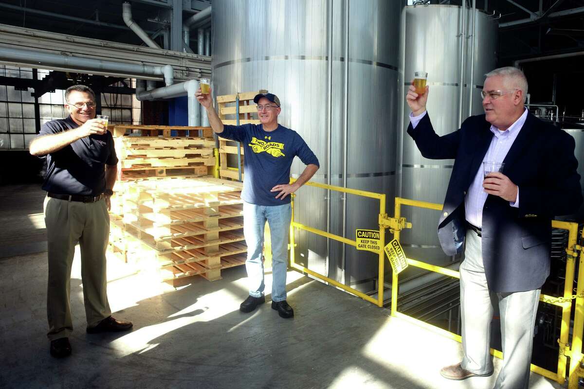 Two Roads Synopsis Red Berries Coming From Area Two / Conn Artists 2021 / Two Conn Ale / Chocolate Cookie Stout / Roadsmary’s Step Child / Roadsmary’s Baby 14 Master Brewer Phil Markowski, center, raises a toast as he leads a tour of the Two Roads Brewing Company brewery, in Stratford, Conn. Oct. 12, 2021. Markowski and Two Roads staff were joined by representatives from the University of Connecticut for the introduction of their new TwoConn Ale.