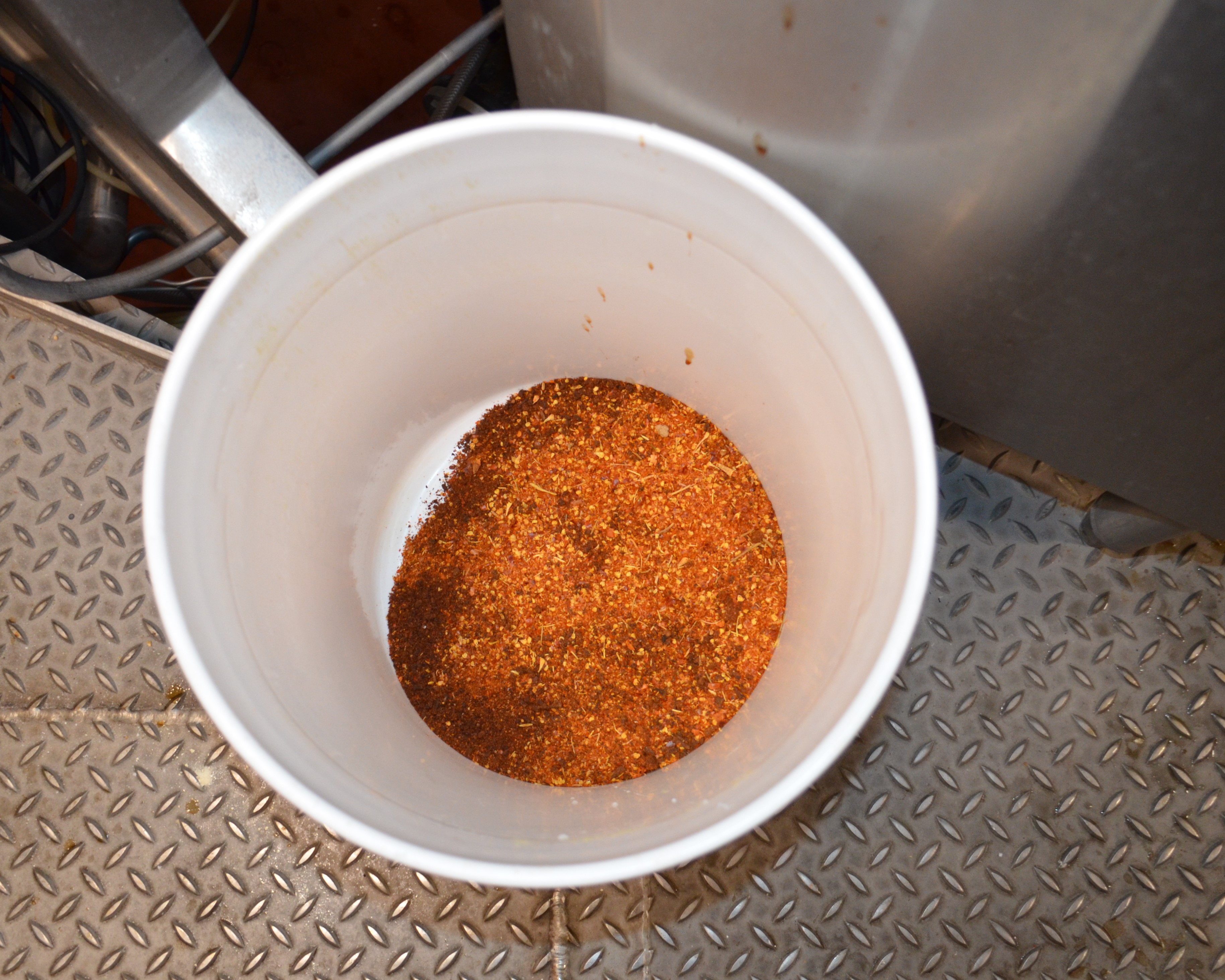 Boulevard Releasing Mexican Xocolatl Ale 21 A white bucket filled with a reddish-brown spice mix sits on a textured metal floor.