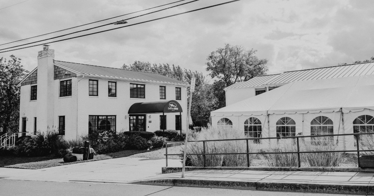 Dogfish Head Weddings - Love is INN the Air 28 a black and white photo of the dogfish inn with a tent in the parking lot