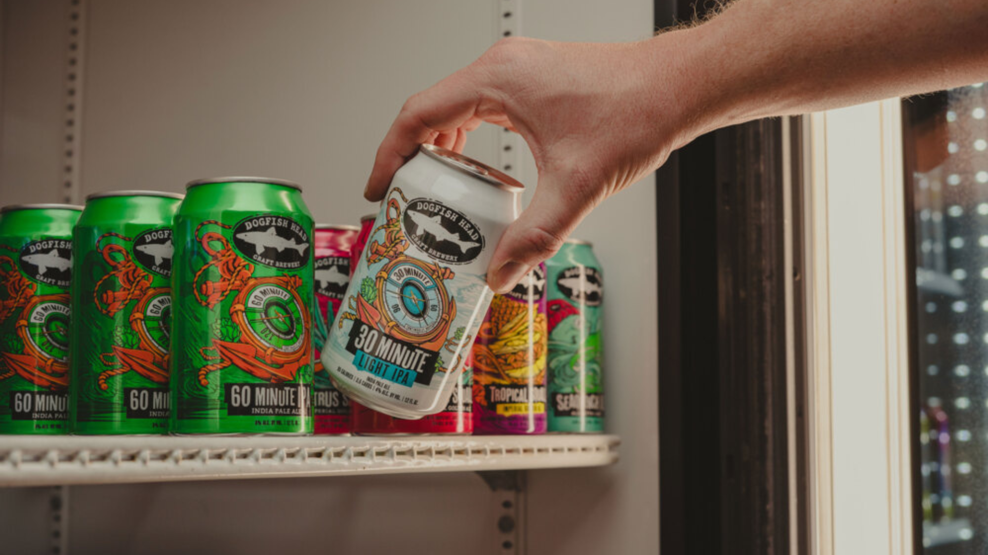 Dogfish Head: Lighten up … it's only Quitter's Day! 12 12 oz can of 30 Minute Light IPA in a refrigerator with a person pulling the can out