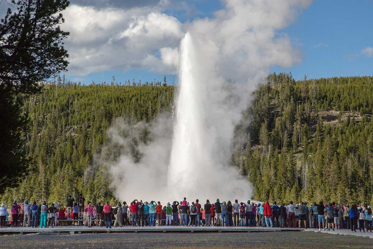 Tourists in front of the erupting Old Faithful geyser Tourists in front of the erupting Old Faithful geyser