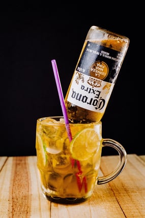 A beer cocktail with a bottle of Corona sticking out of a mug.