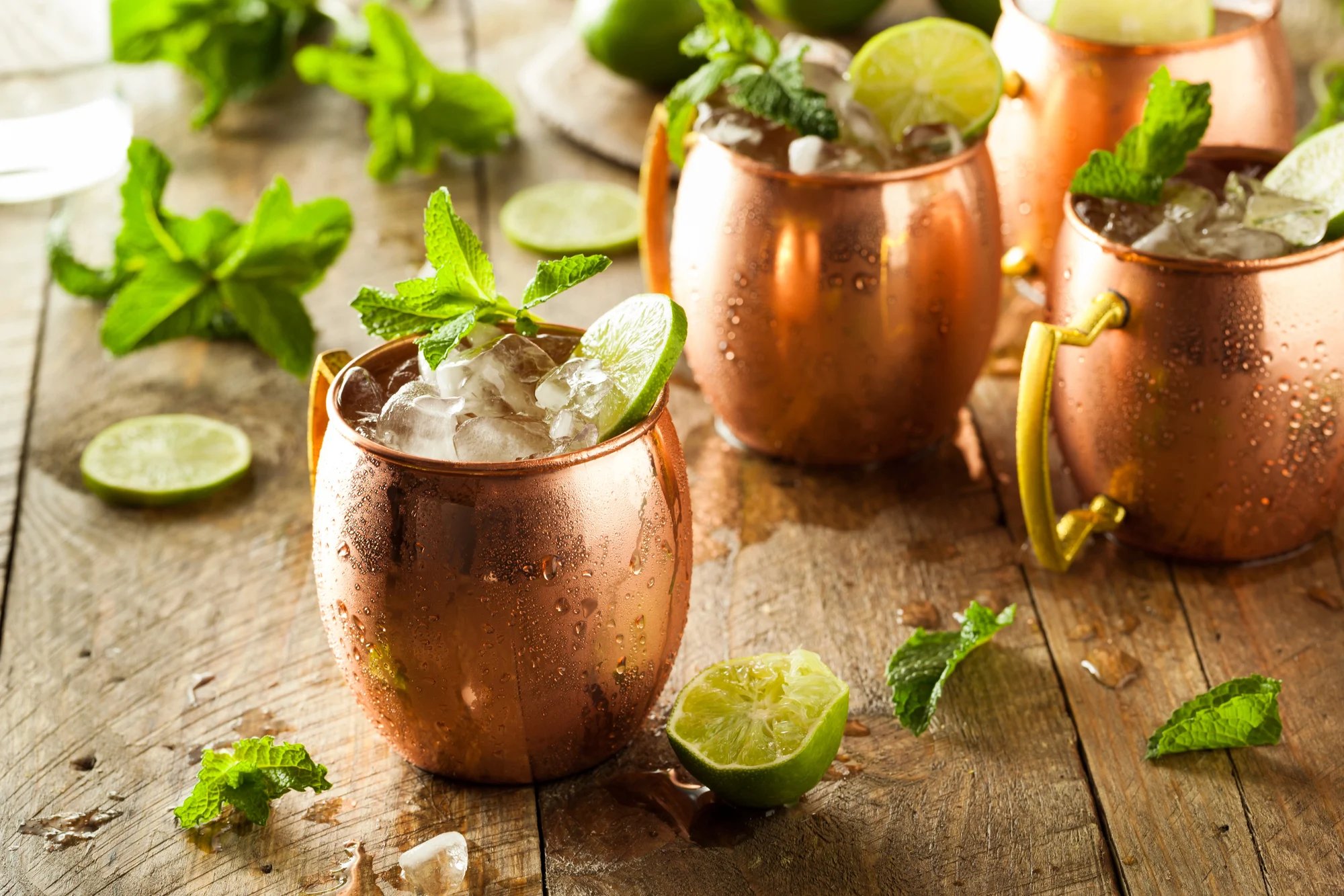 An assortment of ginger beer cocktails arranged on a wooden table.