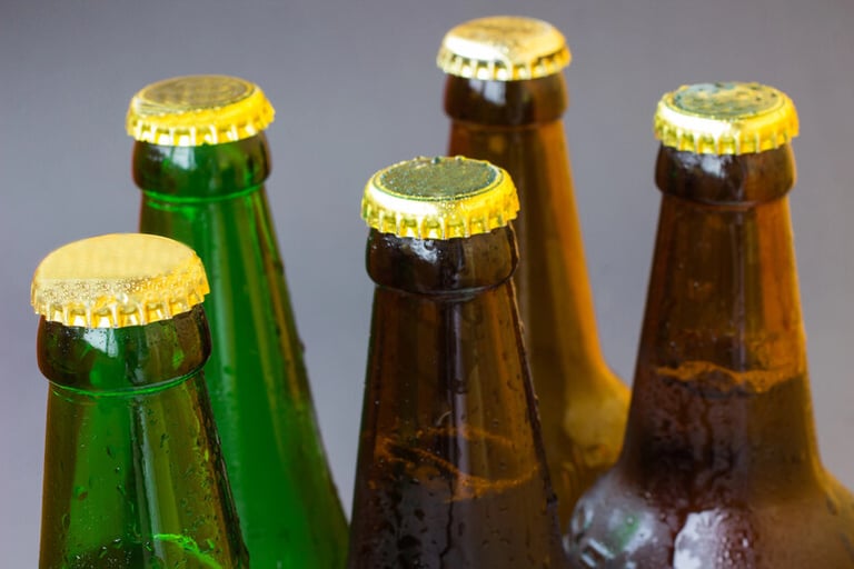 Assorted beer bottles arranged on a rustic wooden table, illustrating beer shelf life, proper storage, freshness, and signs that beer has gone bad.