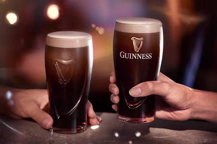 two men hands holding Guinness Draught beer glasses