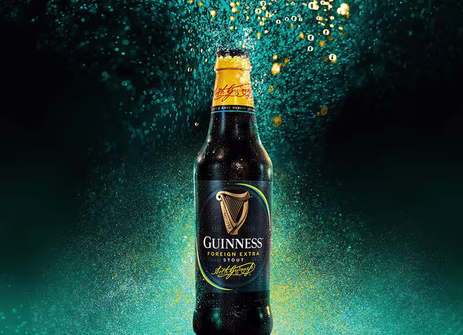 A bottle of Guinness Foreign Extra Stout on a darksparkling green background