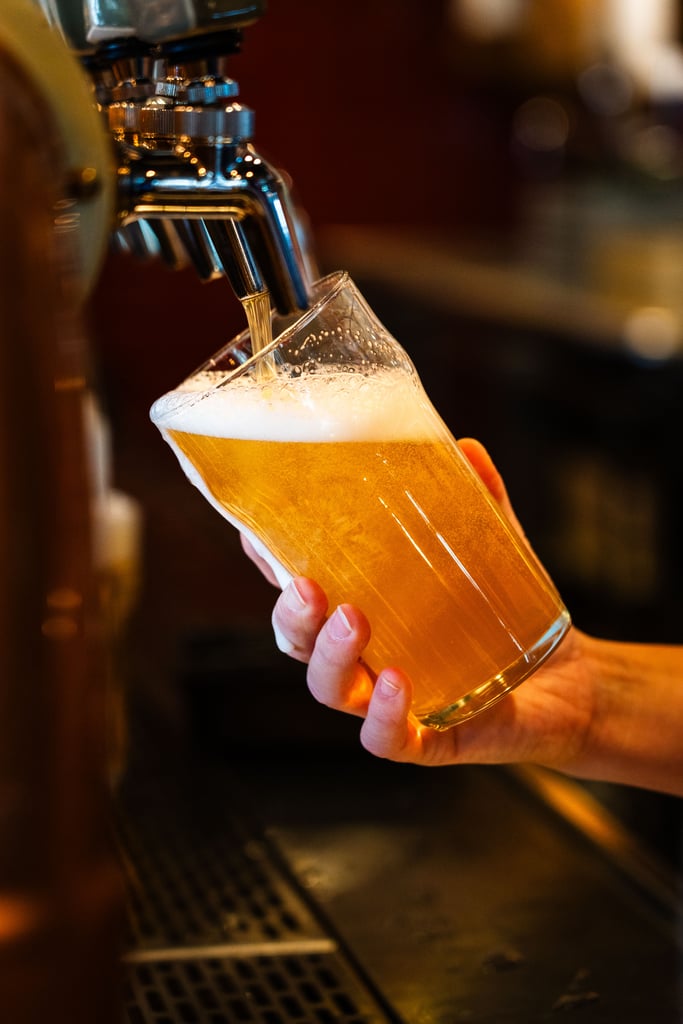 What Are Domestic Beers? Popular American Brands Explained 7 Closeup of a draft beer being poured into a pint glass at a bar in Montreal, Canada.